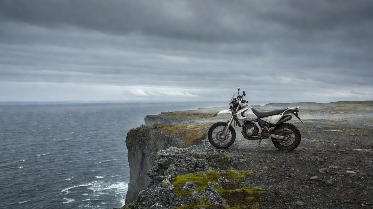Motorcycle parked on the flat Nordkapp plateau near the cliff edge with the Arctic Ocean beyond